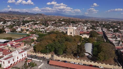 aerial: oaxtepec cityscape with blue cloudy sky during the day in morelos, mexico, pull out drone shot