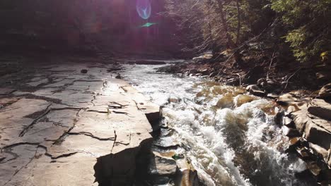 Aerial-view-of-a-mountain-river-with-beautiful-waterfall-in-the-afternoon-sunlight