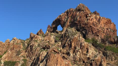 Hole-in-sea-rock-at-Scandola-peninsula-nature-reserve-in-summer-season-as-seen-from-moving-boat,-Corsica-island-in-France