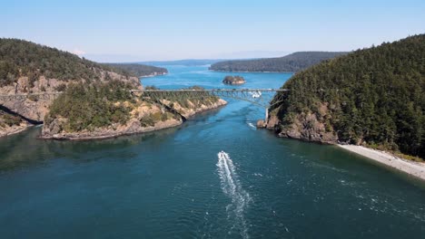 aerial revealing shot of boats passing under the deception pass in washington