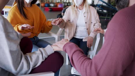 group of people on therapy session, members holding each other by hand.