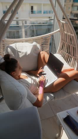 woman working on laptop in a patio swing chair