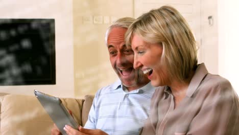 animación del procesamiento de datos sobre una feliz pareja de ancianos caucásicos usando una tableta digital en casa.