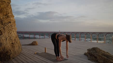 woman practicing downward-facing dog yoga pose at the beach at sunset