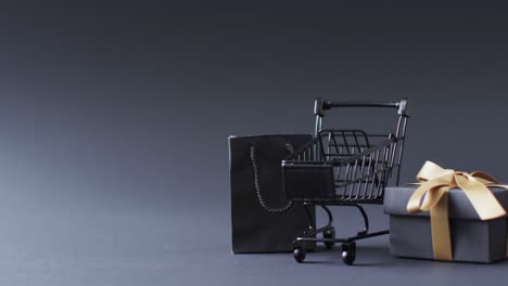 video of shopping trolley, shopping bag and gift box with copy space over grey background