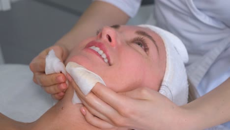 beauty master, cosmetologist wipes a woman’s face with napkins after a mask. rejuvenating procedures for the face. care for the beauty of the face