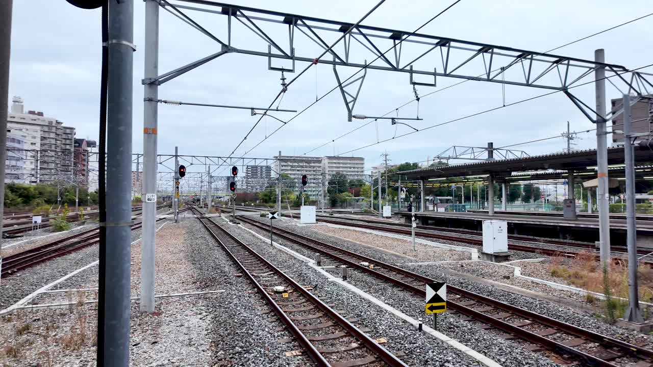 Railway lines with overhead wires extend through a city landscape, showcasing modern urban life.