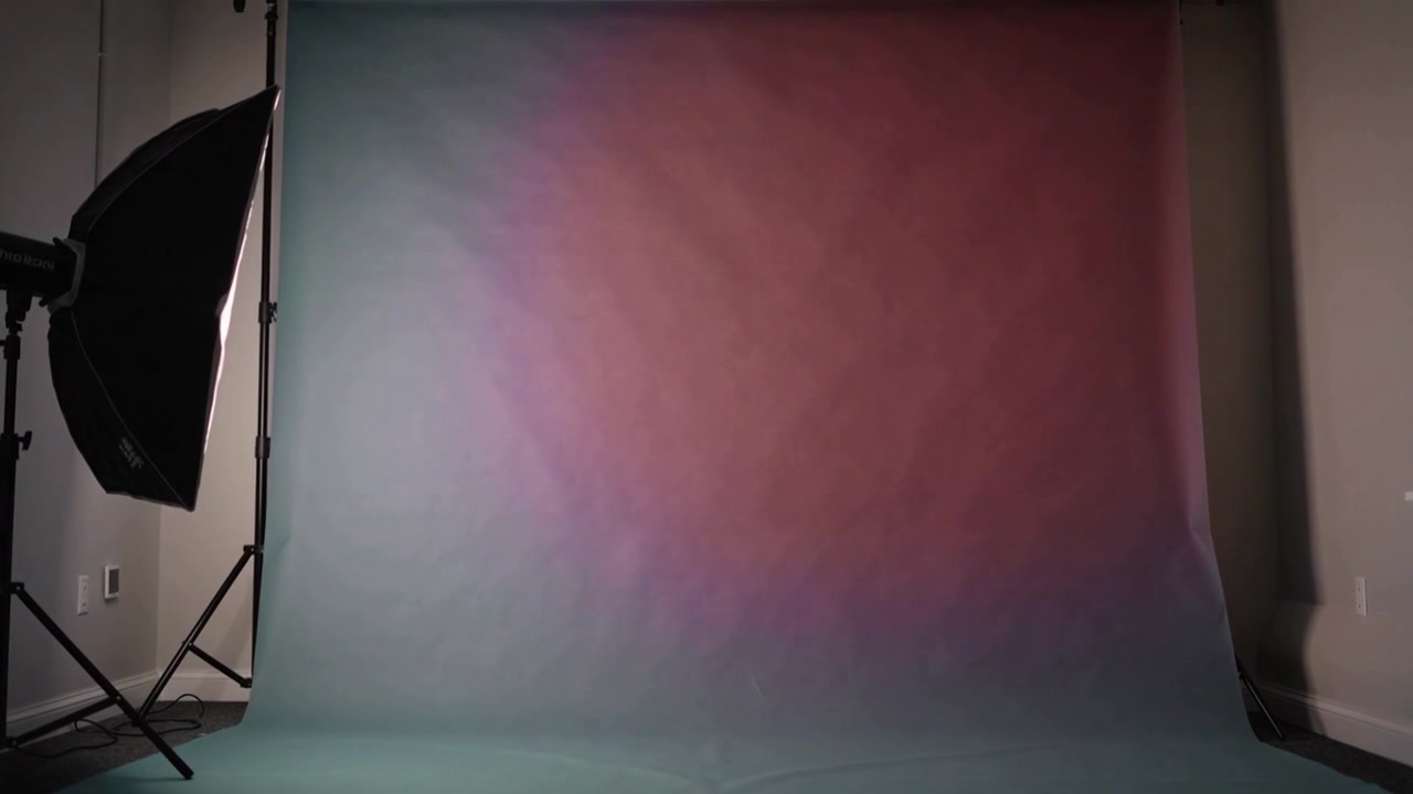 Turning on magenta gel, softbox bathing seamless backdrop teal-to-pink in studio for color change