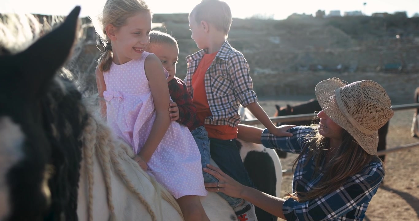 Glad familie med børn rider på hest på en ranch