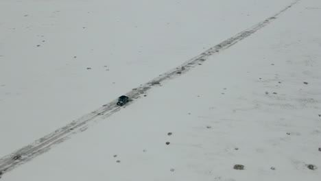 aerial shot looking down as utv side by side drives down snow covered road, 4k