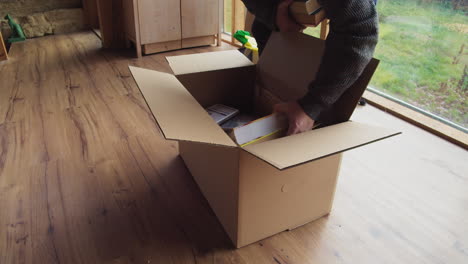 put books in cardboard box , prepare for the move , medium shot