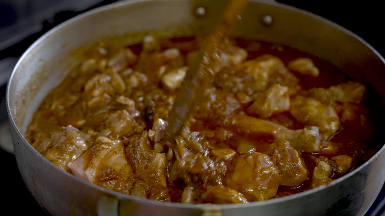 trozos de pollo que se revuelven en una rica salsa de curry hirviendo a fuego lento dentro de una olla grande