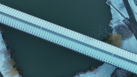 aerial view of birds flying above lake and metro bridge in winter season, suburbs of prague, czech republic