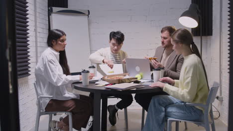 groep multi-etnische collega's die pizza eten tijdens een teamvergadering in de directiekamer