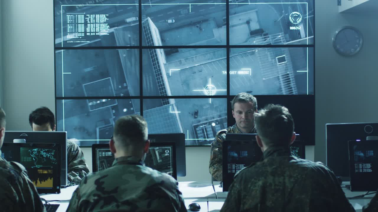 grupo de profesionales militares de ti en una sesión informativa en la sala de monitoreo llena de pantallas en la base militar