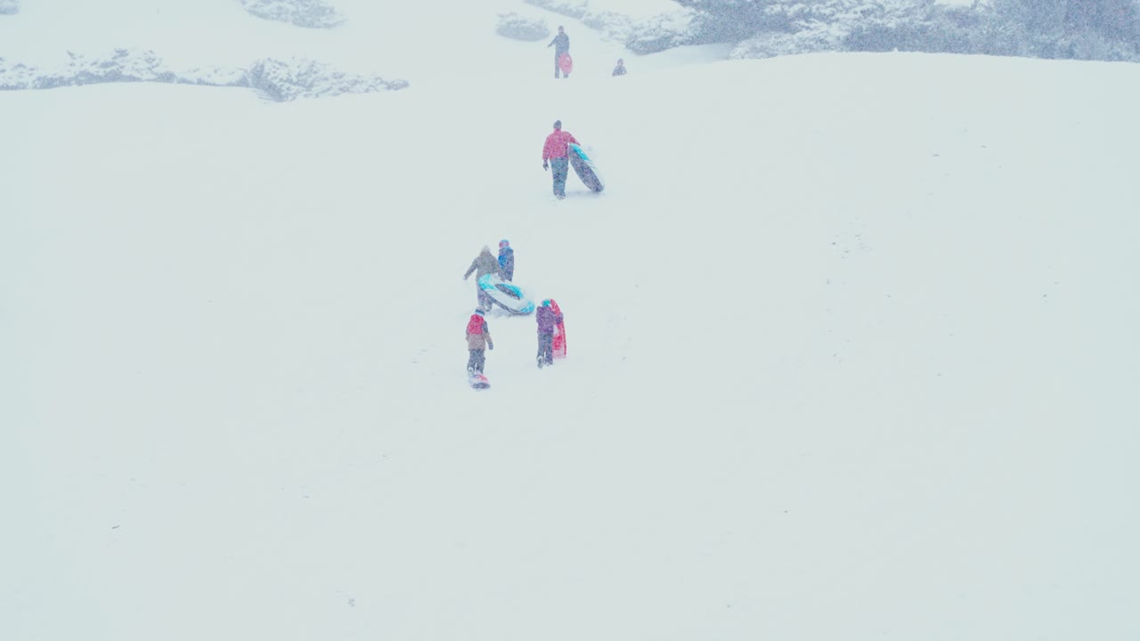 썰매를 끌고 눈 덮인 산을 오르는 사람들