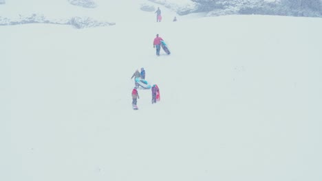 people walking up a snow covered mountain with their sleds in tow