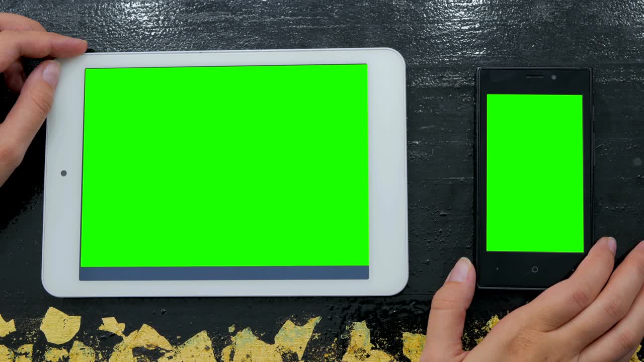 초록색 화면 을 가진 스마트폰 과 디지털 태블릿 을 보고 있는 여자