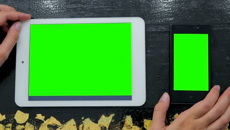 mujer mirando un teléfono inteligente y una tableta digital con pantalla verde