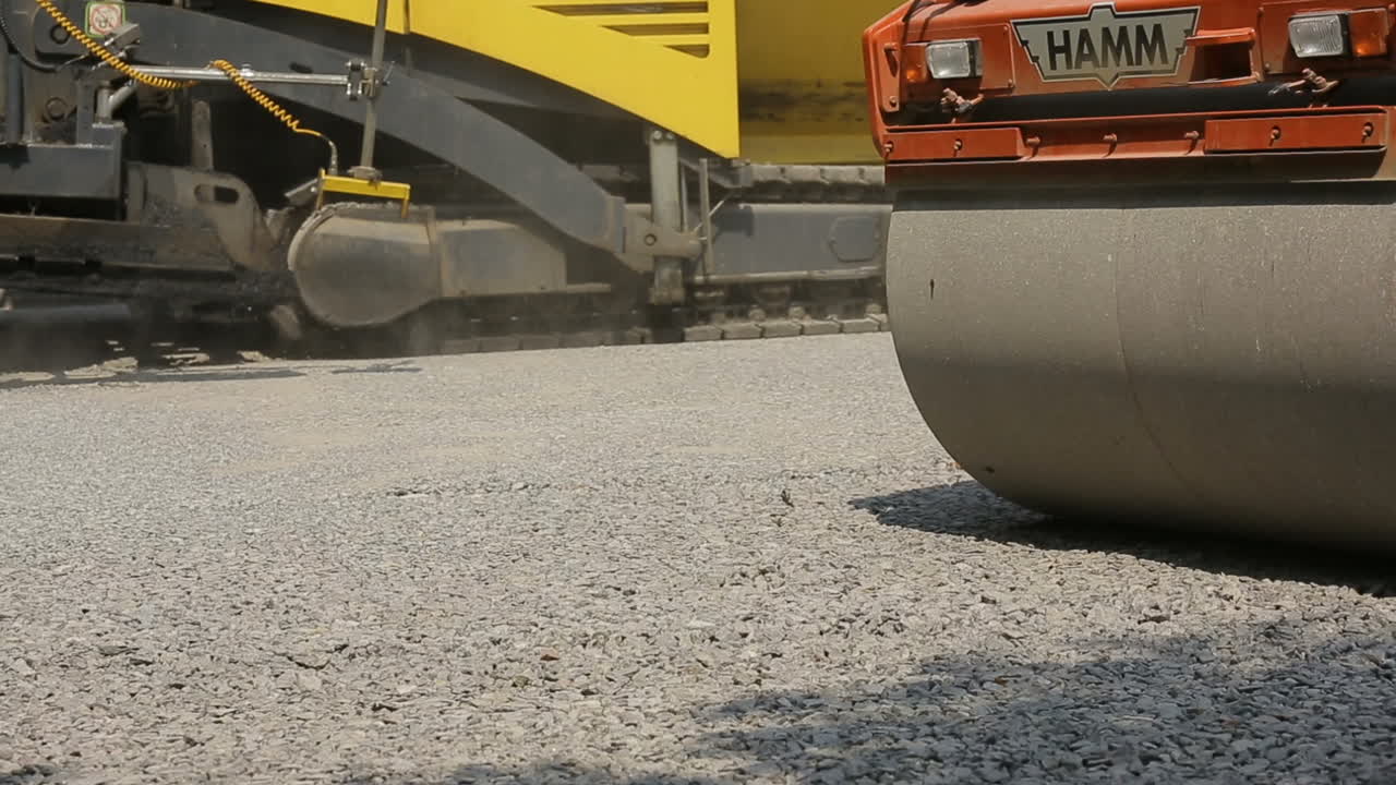 Tracked pavers laying fresh asphalt pavement on a street