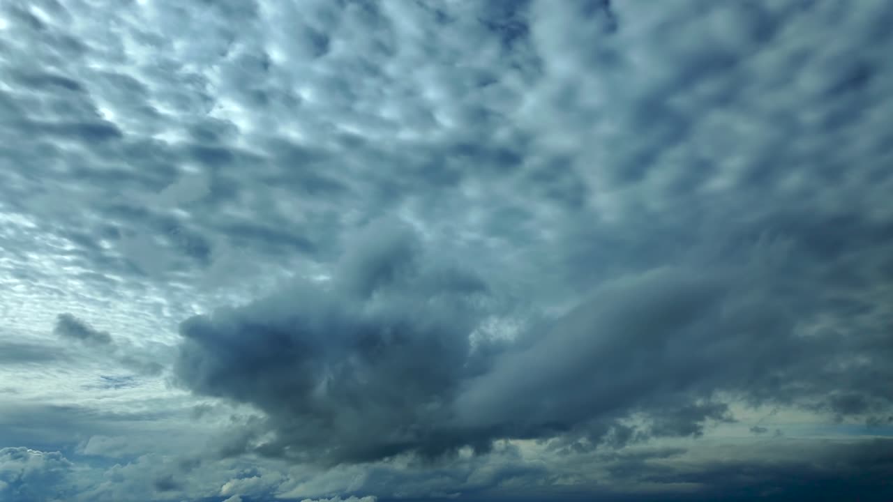 Cockpit view flying under a grey color, manacing sky, as seen by the pilots, with some cumulus clouds floating ahead