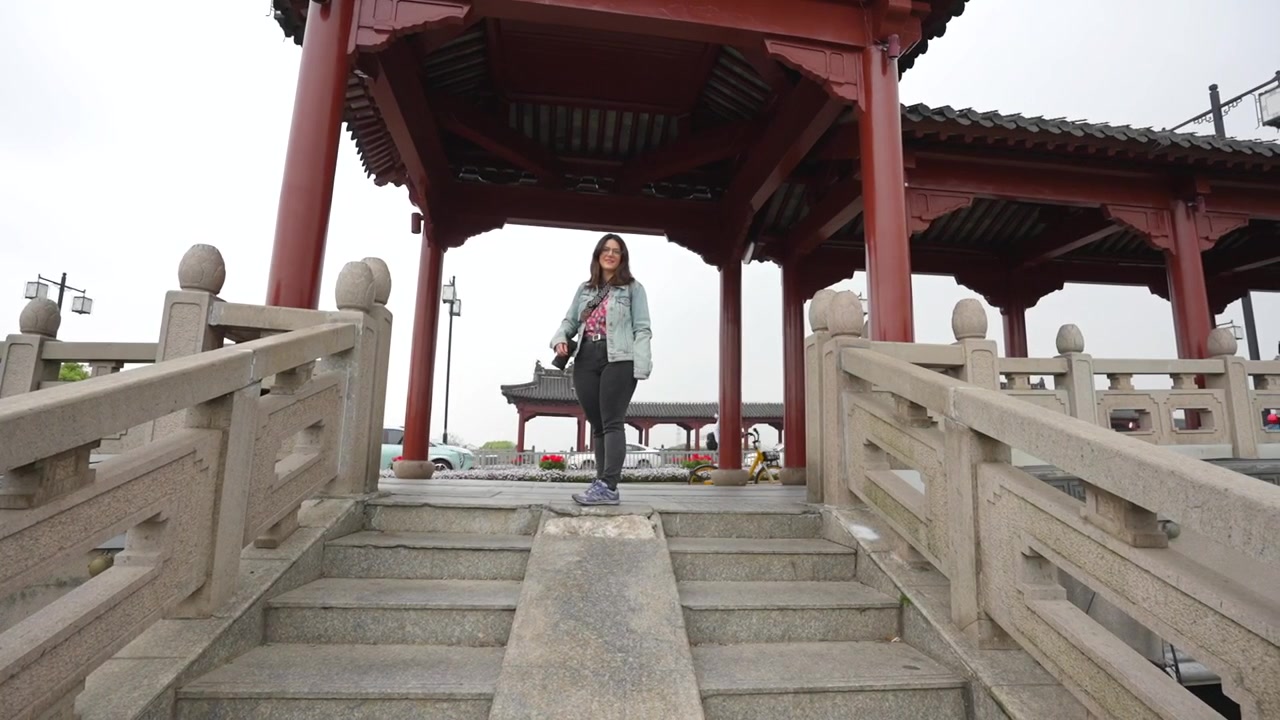 Giovane donna caucasica che scende i gradini di un tradizionale ponte di pietra a Suzhou, Cina.