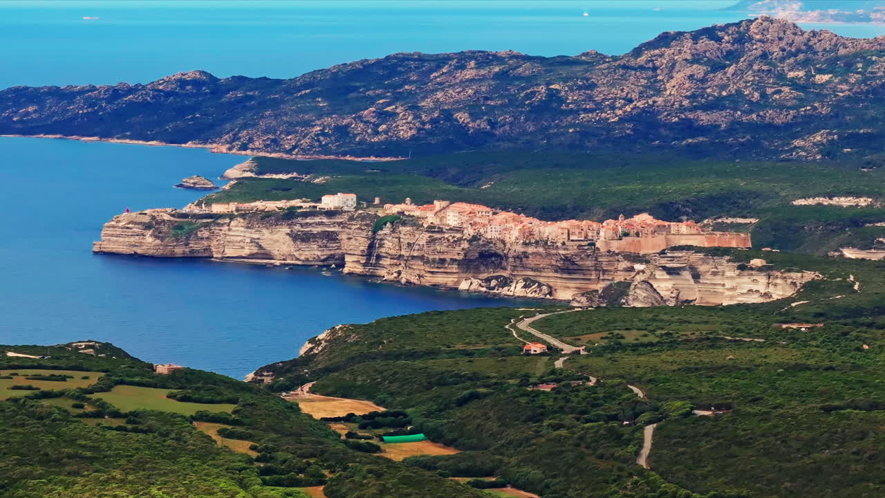 Aerial drone shot over the historic coastal town of Bonifacio in Corsica, France. High view of the rocky steep cliff and the turquoise sea. Ancient Citadel overlooking the rugged coastline