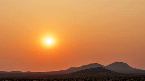 The-sun-rises-like-a-glowing-ball-as-it-elevates-over-the-mountain-desert-landscape-in-this-colorful-time-lapse