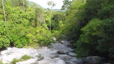 Rocky-stream-surrounded-by-dense-greenery-in-the-tropical-forests-of-Minca,-Colombia,-aerial-view