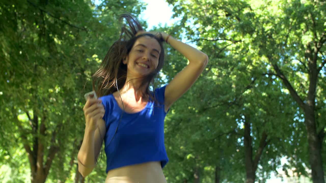 Charming female runner listening music during jogging