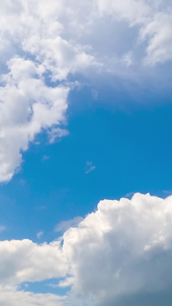 White cotton clouds soaring in the blue sky. Little clouds gathering into a big cloudscape. Timelapse. Vertical video