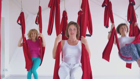 women have fun swinging on red hammocks in spacious room