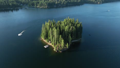 drone shot of a boat circling an island in a lake