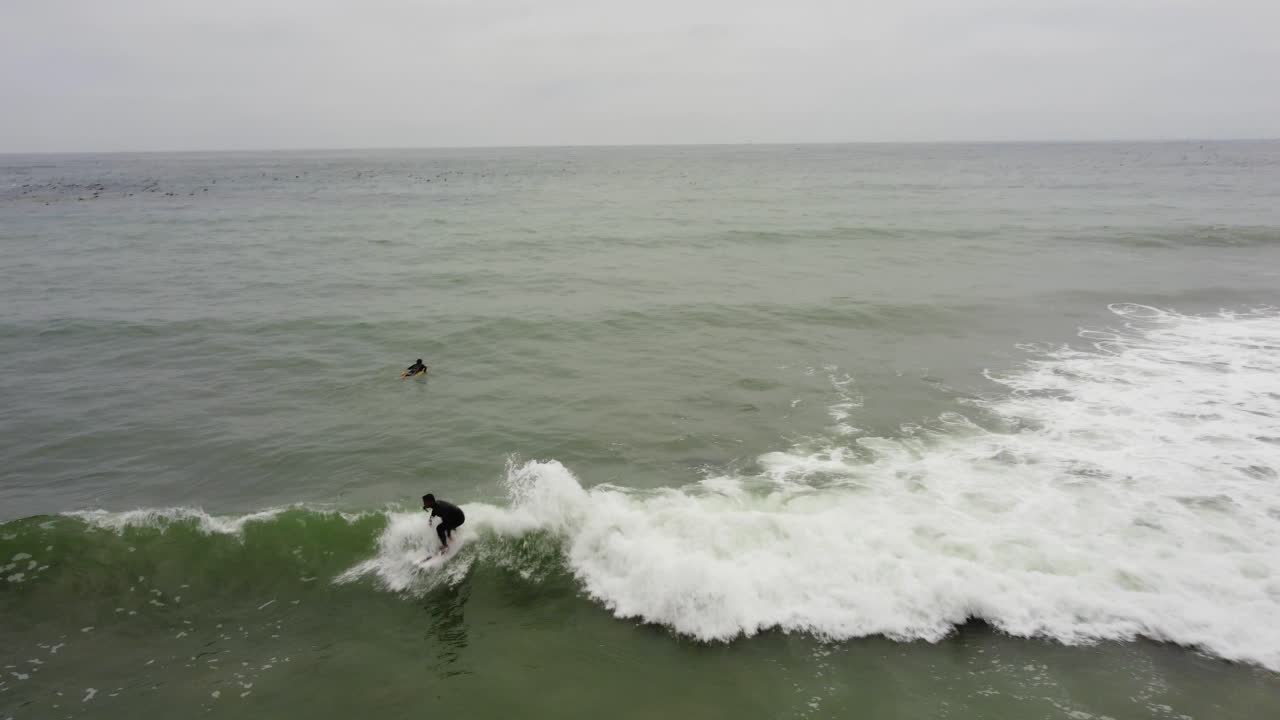 무인 항공기가 머리 위로 날아가는 서퍼가 파도를 타고 좌회전하는 동안 파도를 타는 서퍼를 잡는 서퍼