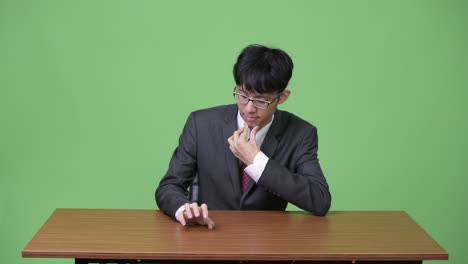 젊은 아시아 사업가 지루하고 테이블에 손가락을