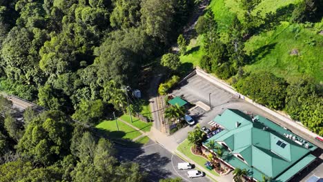 aerial footage captures a vibrant landscape with green-roofed buildings surrounded by dense forest in uki, nsw, australia