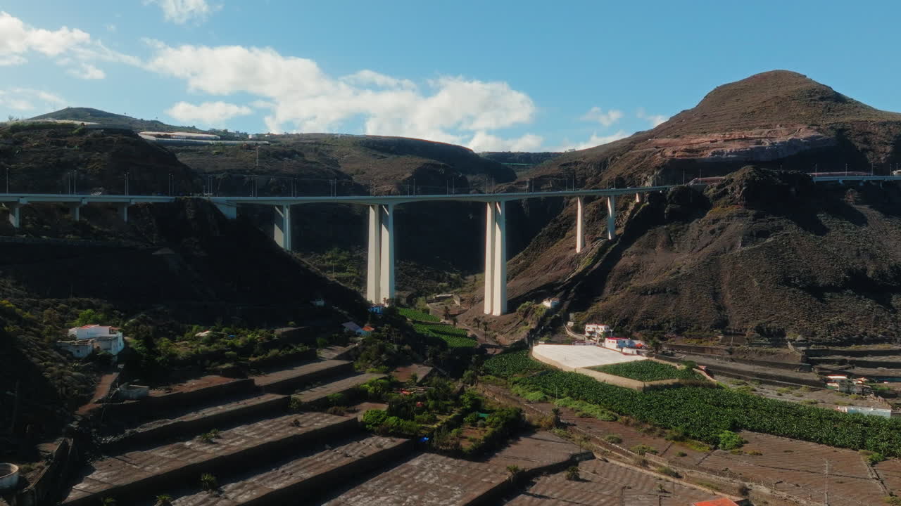 Aerial: white bridge in a valley during the day in Gran Canaria, Spain, push in drone shot