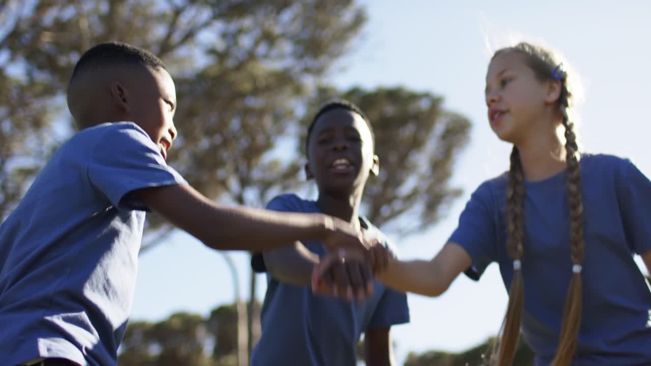 African American kids stacking hands, camera rising, raising arms, cheering on field in blue shirts
