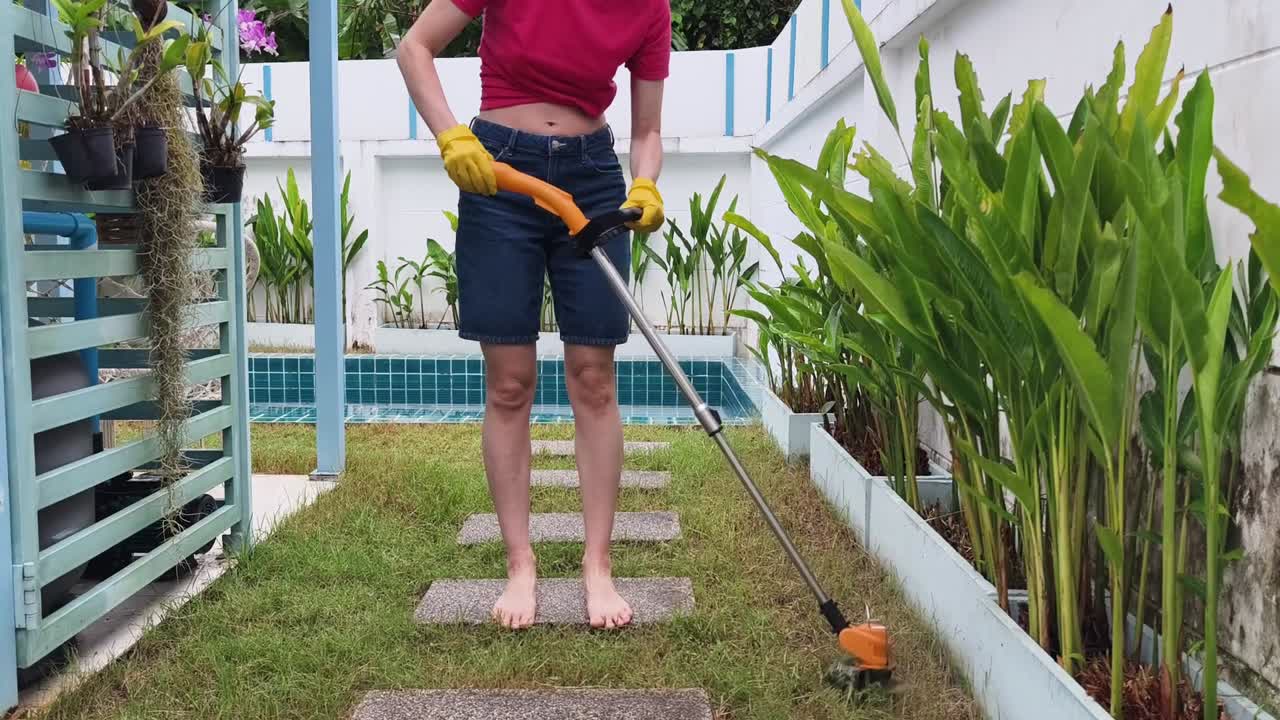 A woman weed whacking the lawn in her garden