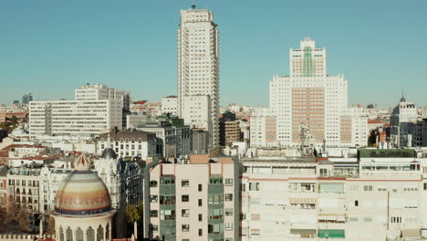 Fly-above-town-buildings-around-colourful-dome-of-Church-of-Saint-Theresa-and-Saint-Joseph.-Revealing-Spain-square-with-tall-buildings-around.