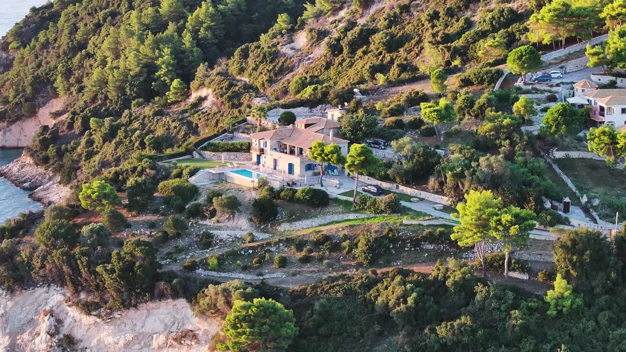 Wunderschöne mediterrane Villa mit einem Infinity-Pool am Rande einer Klippe am Ionischen Meer von Zakynthos, Griechenland, üppiges Grün, Terrakottadach. Luftaufnahme, Kamerafahrt nach links, Schwenk nach rechts.
