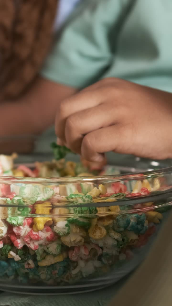 Child's Hand Grabbing Colorful Popcorn from a Bowl