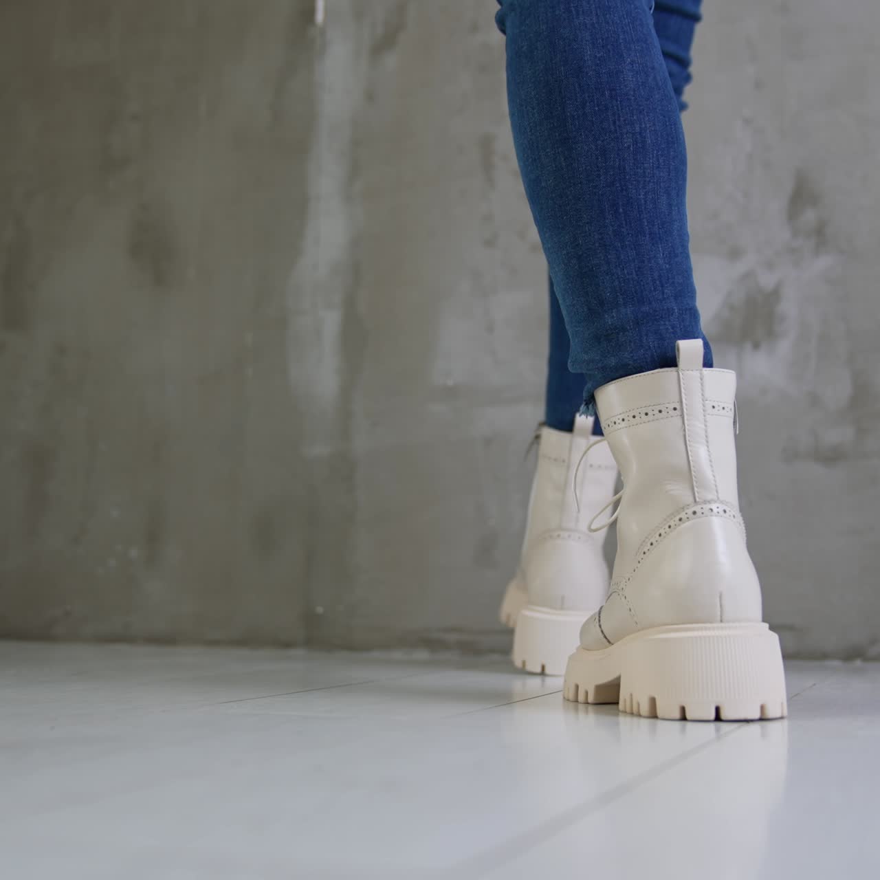 White leather army boots on a female wearing jeans. Woman demonstrating stylish footwear in the studio