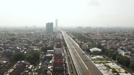 aerial view over highway with buildings and houses in jakarta downtown, indonesia - drone shot