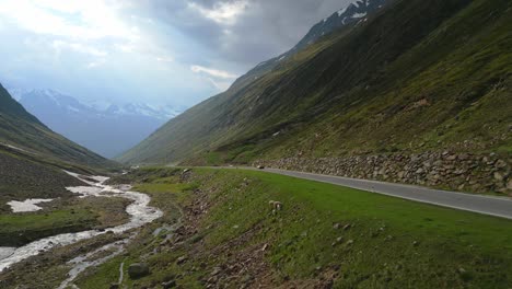 una toma cercana de un avión no tripulado cinematográfico de un solo coche a través de una carretera de montaña en los alpes