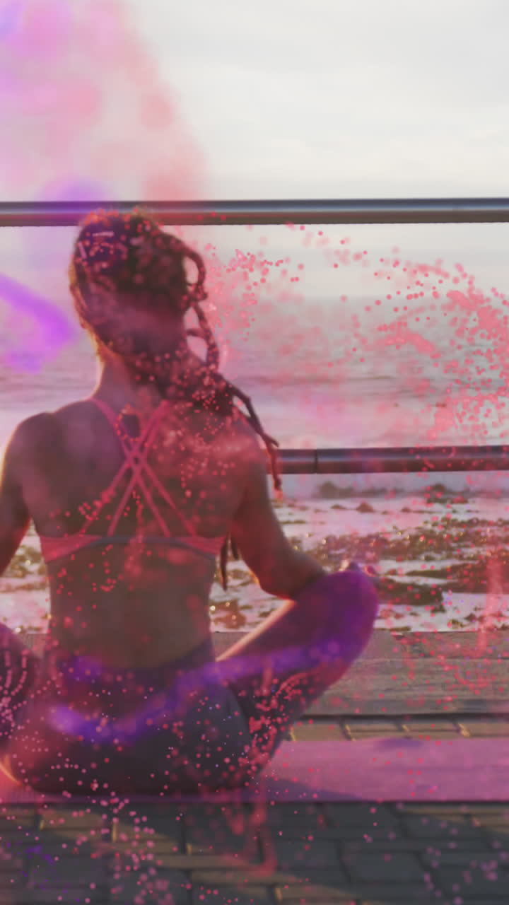 Animazione di macchie colorate su una donna birazziale che medita in riva al mare.