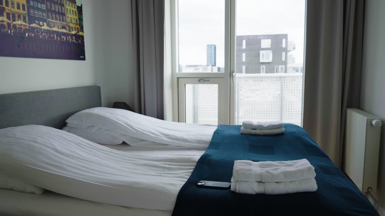 Beautifully made bed at hotel bedroom with large window, Copenhagen