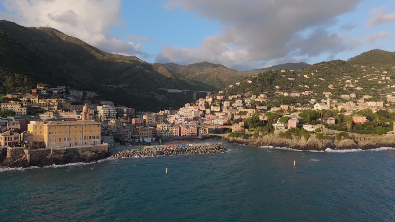 A coastal town in Genoa with colorful houses and scenic hills by the blue sea at sunset