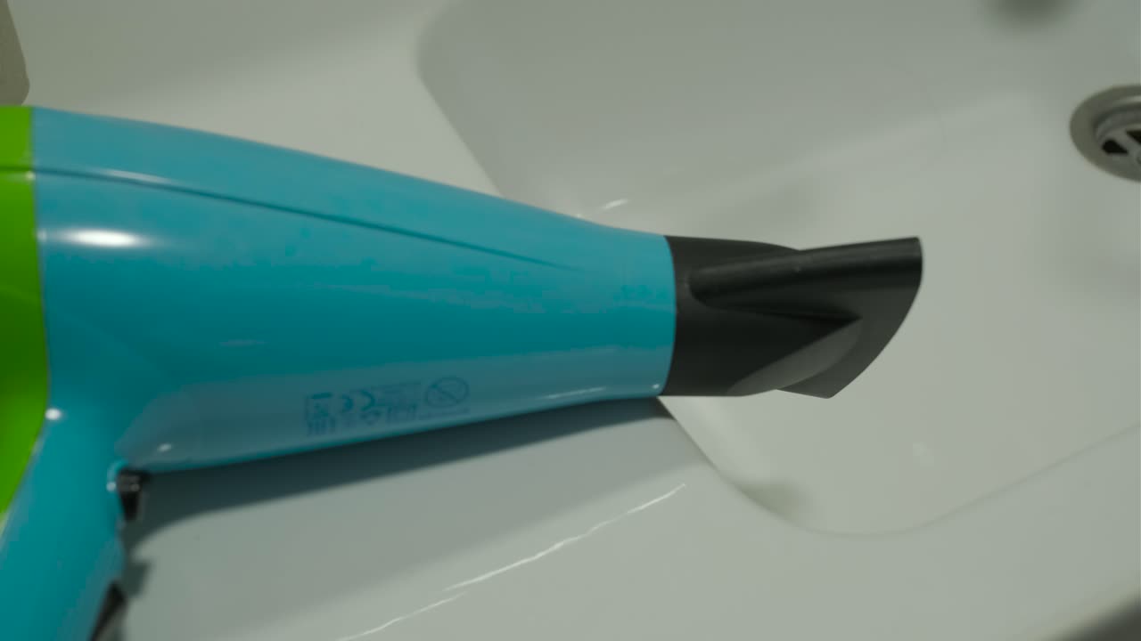 Plano detalhe de um secador de cabelo azul e verde em funcionamento.