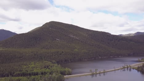 Vehicles-on-highway-built-on-causeway-across-small-lake-in-the-Rockies